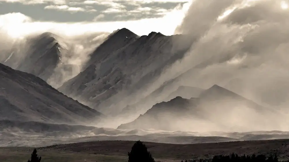 Sharp mountain ridges half hidden in drifting cloud, in black and white